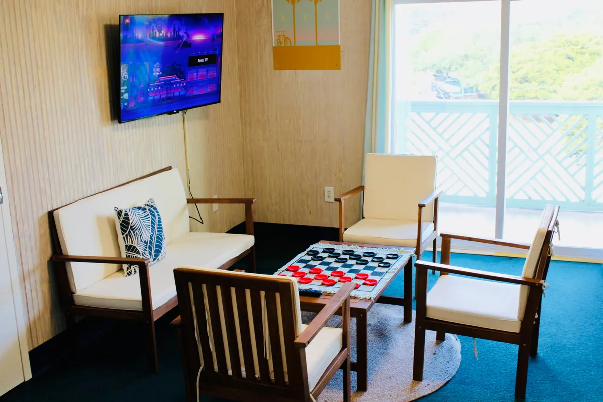 The image showcases a cozy interior with a checkerboard table set up for games, comfortable seating perfectly arranged for conversation or relaxation, and a TV ready for entertainment—all inviting guests to unwind and enjoy quality time together.